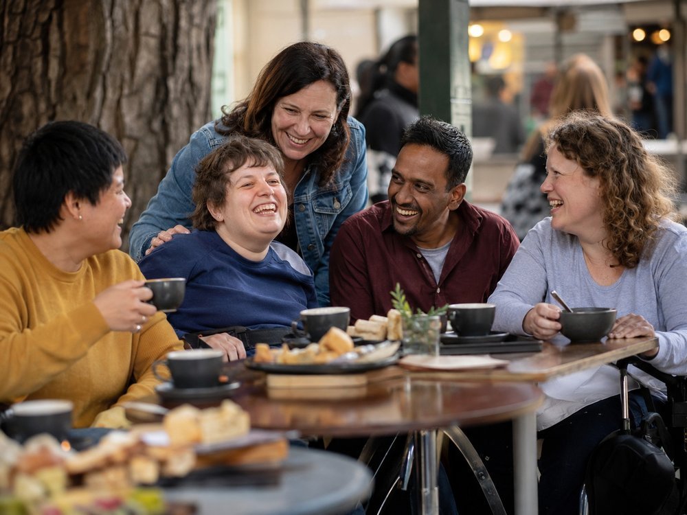 A participant and support worker laughing together at a local community market